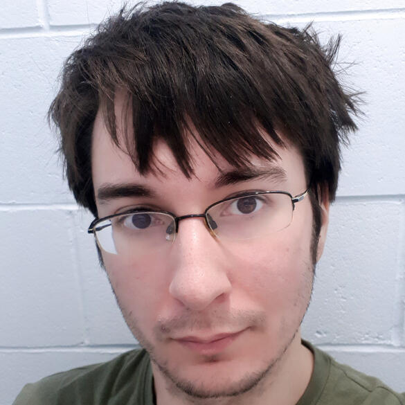 Photo of Devon Black in a shirt in front of a wall.